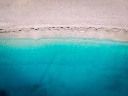 Top-down aerial view of a clean white sandy beach on the shores of a beautiful turquoise sea. Greece.の写真素材