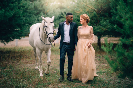 Happy couple walking together on ranch with horses at sunset