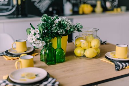 Kitchen table with plates and mugs with yellow and green decor. Close up.の写真素材