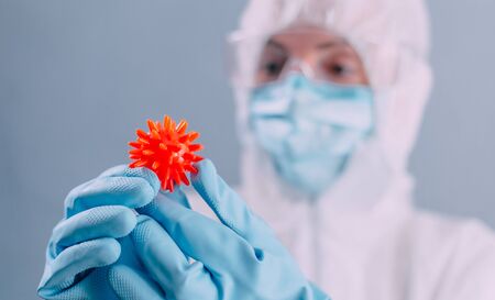 Doctor virologist in a protective suit holds a dangerous virus in his hands.. Close up.の写真素材