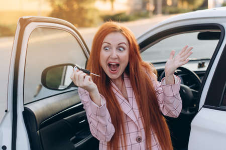 Woman won car. Happy winner holds keys in his hands while standing near car.の写真素材