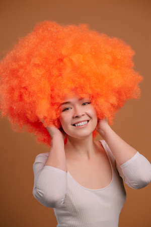 Smiling young orange haired woman on beige background. Close up portrait.の写真素材