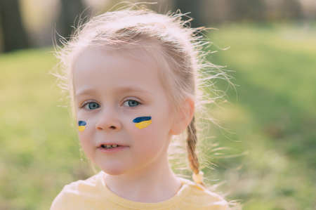 Portrait of Ukrainian little girl. National flag of Ukraine is painted on girls face.の写真素材