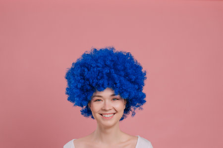 Close-up Portrait of Young Smiling Woman In blue Wig. Millennial female with blue curly hair.の写真素材