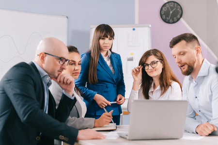 A team of business people are discussing the project together in the office. The team sits at a...