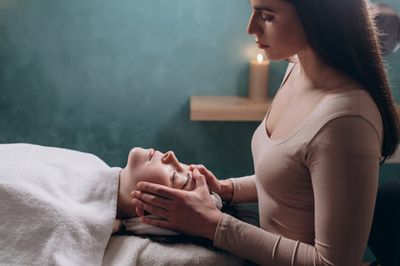 The beautician makes a deep facial massage to a young woman. Face massage technique against aging.の写真素材