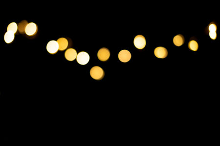 Golden blurred bokeh lights on black background. Christmas lights overlay.