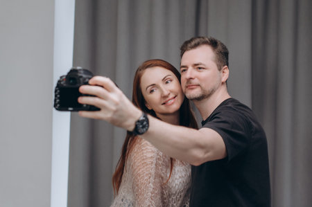 A photographer and a female model take a selfie together in a professional studio, smiling during a relaxed behind-the-scenes photoshoot moment.の写真素材