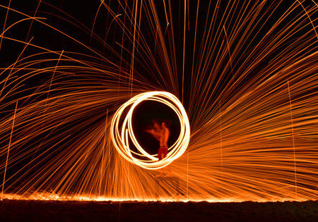 Fireman Show on the beach dance man juggling with swing fire sparks in the night, Thailand