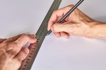 Hands marking a white board, ruller and pencil on a green matの写真素材