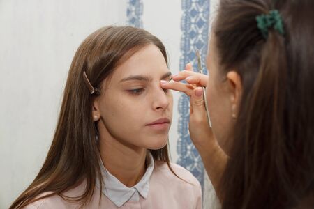 The process of removing excess tone cream. Makeup artist removes excess tone cream from model's face. Makeup artist aligns tonal crem on the face of the model. Applying tone to the skin.の写真素材