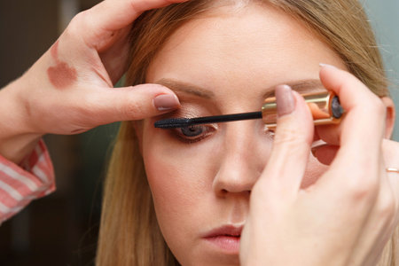 Makeup artist creates voluminous eyelashes of the model.