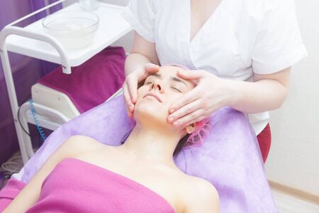 The master conducts the face preparation procedure. Preparation of the client for buccal massage.. cosmetologist makes a buccal massage of the patient's facial muscles.の写真素材