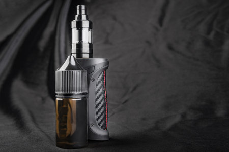 Black vape with oil on a black background close-up. Packaging plastic Bottle vape blank label, Mock...
