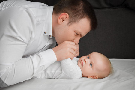 A young father bent at the little baby, at home.