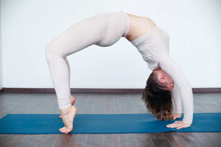 Beautiful girl practices kundalini yoga indoors in daylight.