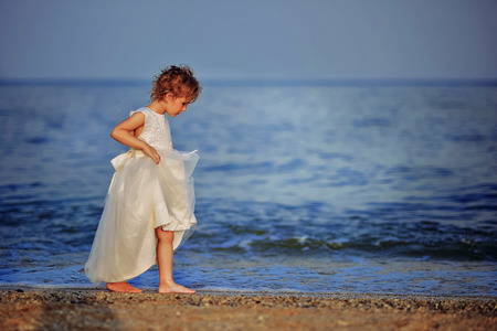 girl in white dress walking barefoot on the beachの写真素材