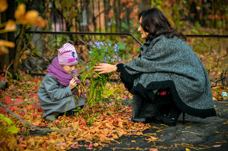 mother communicates with her daughter and is holding a live flower growing out of soilの写真素材
