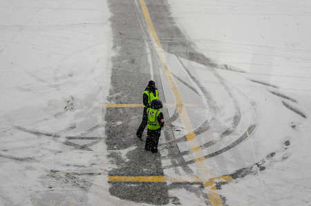 Airport Workers Having a Conversation While Waiting for the Airplane in Bad Winter Weather with a lot of Snow. JFK Airport, New York City, USAのeditorial素材