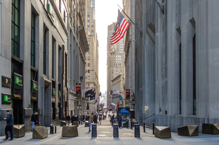 The Famous Wall Street with the USA Flag Waving Proudly. Pedestrians, Visitors and Locals Walking Through the Street. Financial District, Manhattan, New York City, USAのeditorial素材