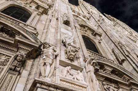 Detailed Low Angle View of Duomo Milan Cathedral Church in Milan, Lombardy, Italy. Beautiful Artwork on the Wall of the Facade.の写真素材