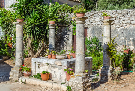 Garden Decoration in an Old Greek Monastery Backyard in Zante Island, Greece. Four Columns and a Stone Monument in the Center.の写真素材