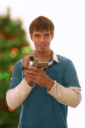 happy guy holding a camera; blurred christmas tree backgroundの写真素材