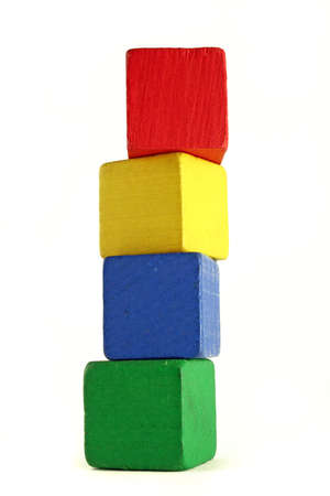 four wooden childrens blocks of different colors stacked in a high tower - low camera angle to emphasize heightの写真素材