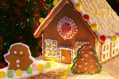 festively lit homemade gingerbread house with snowman, christmas tree and decorationsの写真素材