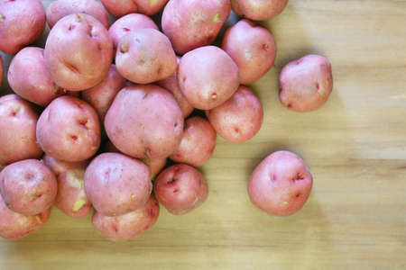 Fresh unpeeled red potatoes spilled on a wooden backgroundの写真素材