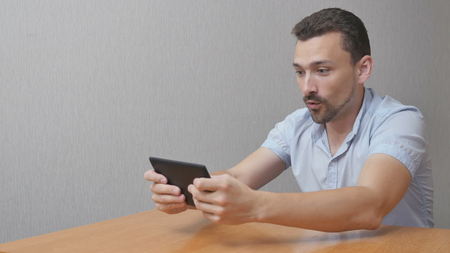 Man plays a game on the tablet and admires. Someone is happily using the device to satisfy themselvesの写真素材