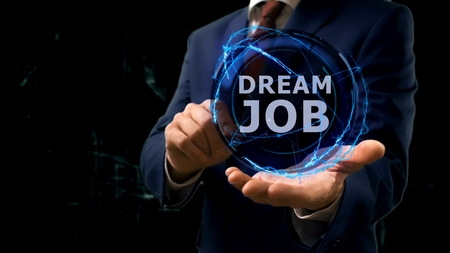Businessman shows concept hologram Dream job on his hand. Man in business suit with future technology screen and modern cosmic backgroundの写真素材