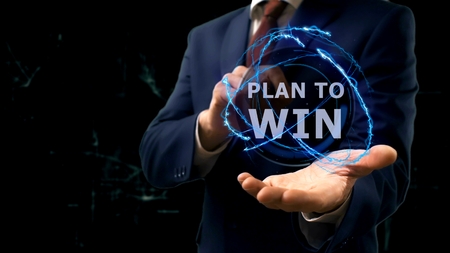 Businessman shows concept hologram Plan to win on his hand. Man in business suit with future technology screen and modern cosmic backgroundの写真素材