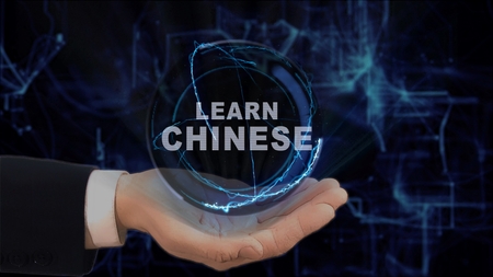Painted hand shows concept hologram Learn Chinese on his hand. Drawn man in business suit with future technology screen and modern cosmic backgroundの写真素材