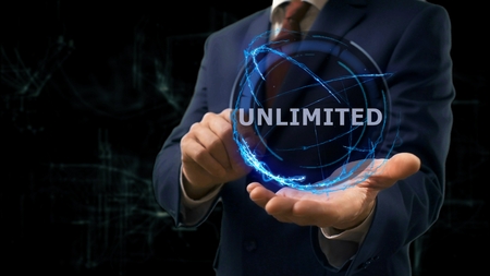 Businessman shows concept hologram Unlimited on his hand. Man in business suit with future technology screen and modern cosmic backgroundの写真素材