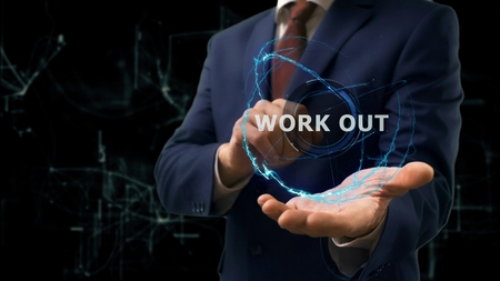 Businessman shows concept hologram Work out on his hand. Man in business suit with future technology screen and modern cosmic backgroundの写真素材
