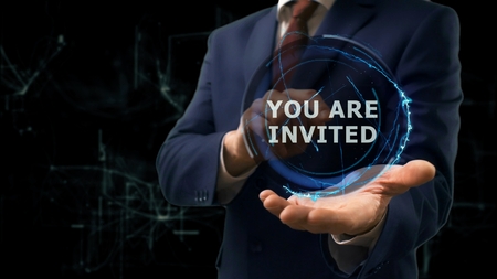 Businessman shows concept hologram You are invited on his hand. Man in business suit with future technology screen and modern cosmic backgroundの写真素材
