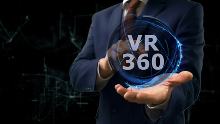 Businessman shows concept hologram VR 360 on his hand. Man in business suit with future technology screen and modern cosmic backgroundの写真素材