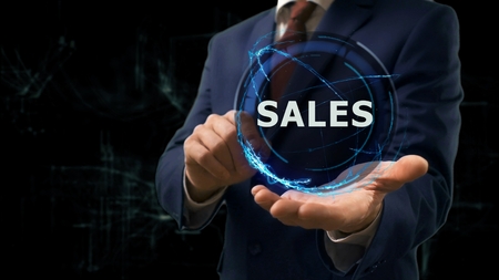 Businessman shows concept hologram Sales on his hand. Man in business suit with future technology screen and modern cosmic backgroundの写真素材