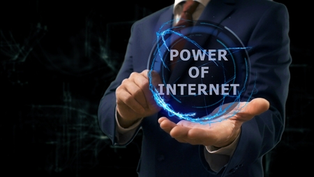 Businessman shows concept hologram Power of internet on his hand. Man in business suit with future technology screen and modern cosmic backgroundの写真素材