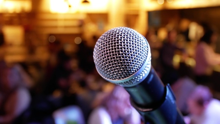 Microphone on the background of the hall with people with blurred bokehの写真素材