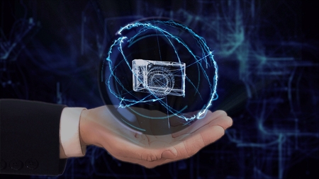 Painted hand shows concept hologram 3d pocket camera on his hand. Drawn man in business suit with future technology screen and modern cosmic backgroundの写真素材