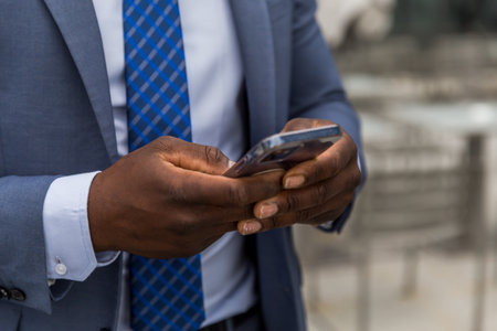 Close-up of businessman using mobile phone while standing in outdoor cafeの写真素材