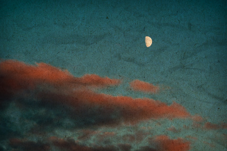 Summer sky with red clouds and a big moon at sunset.の写真素材