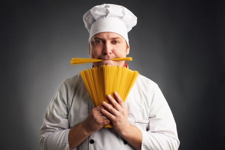 funny cook with spaghetti in his mouth on grey backgroundの写真素材