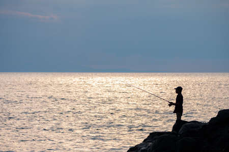 Silhouette of fisherman, he is fishing in Lombok, Indonesiaの写真素材