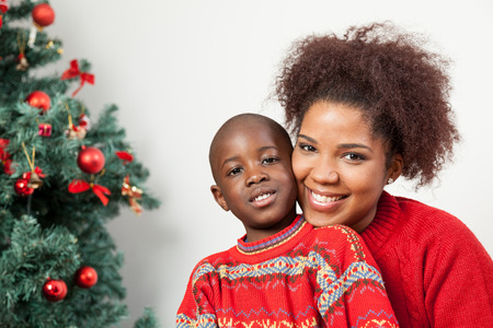 Black boy with his mother near the treeの写真素材