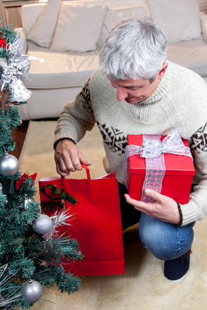 Man putting the gift under the christmas treeの写真素材