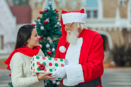 Santa claus giving to a young woman a christmas presentの写真素材