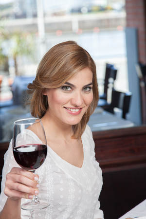 Pretty woman toasting with a glass of wineの写真素材